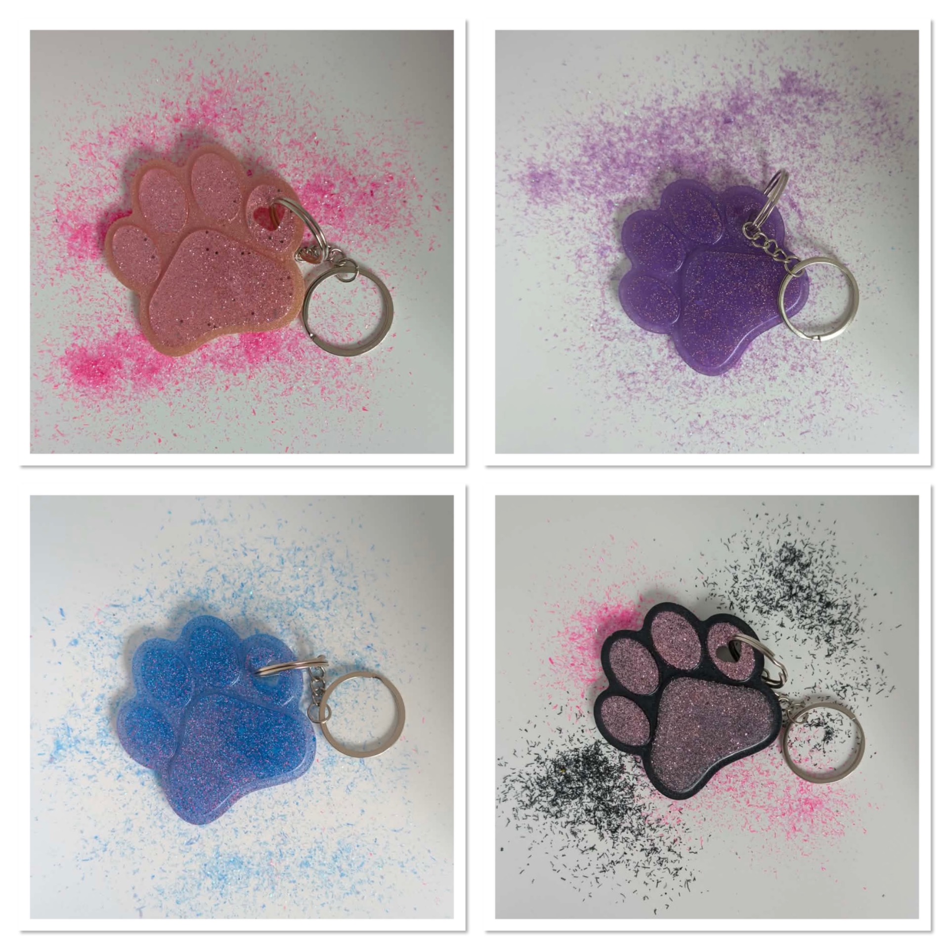 Four glitter paw-shaped keychains in pink, purple, blue, and black with metal rings on speckled backgrounds.
